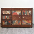 Wooden dresser with geometric patterned doors on a gray floor and white wall