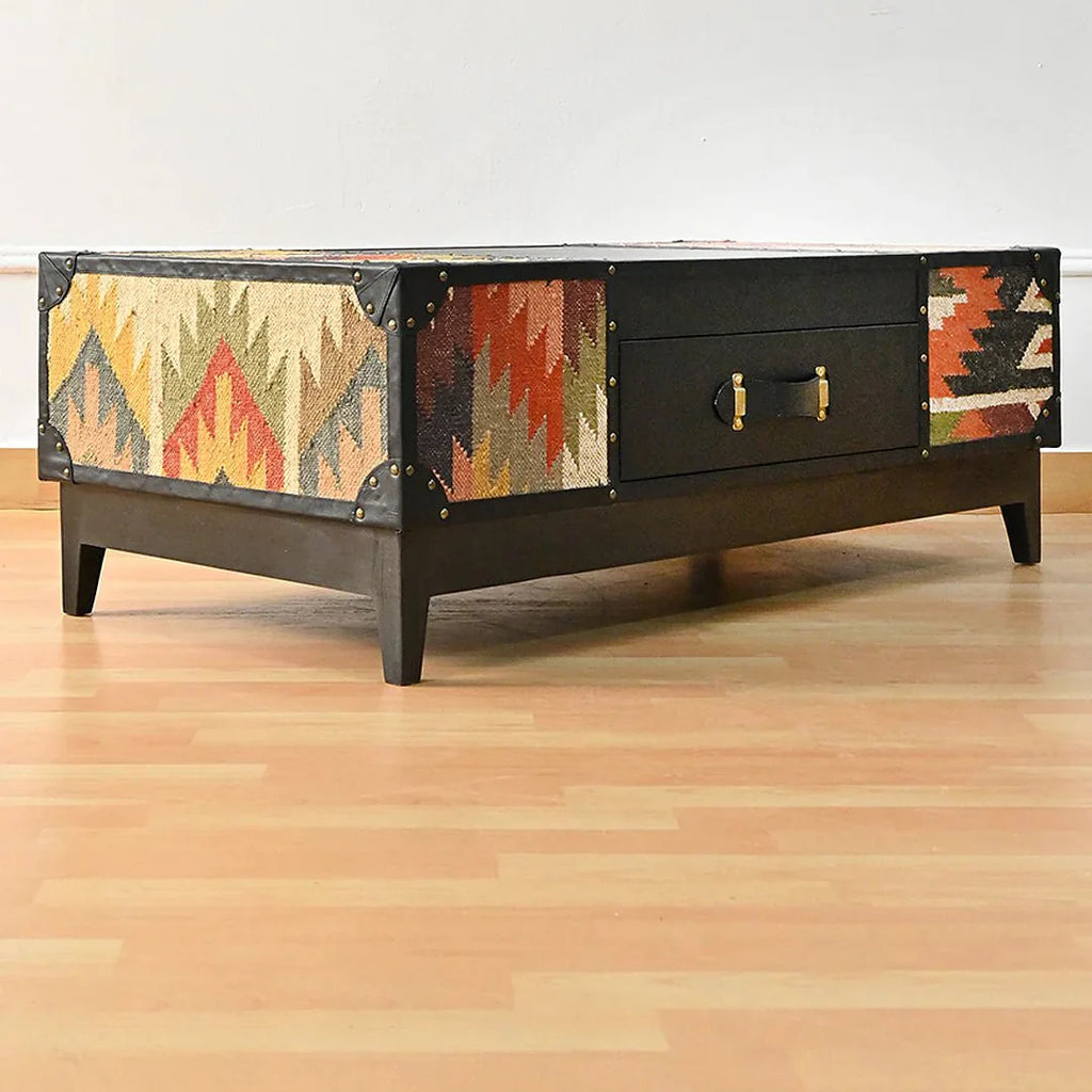 Wooden coffee table with patterned side panels on a wooden floor.