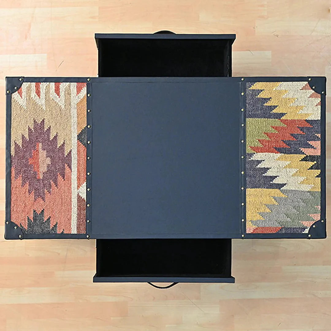 Black storage coffee table with patterned side panels on a wooden floor.