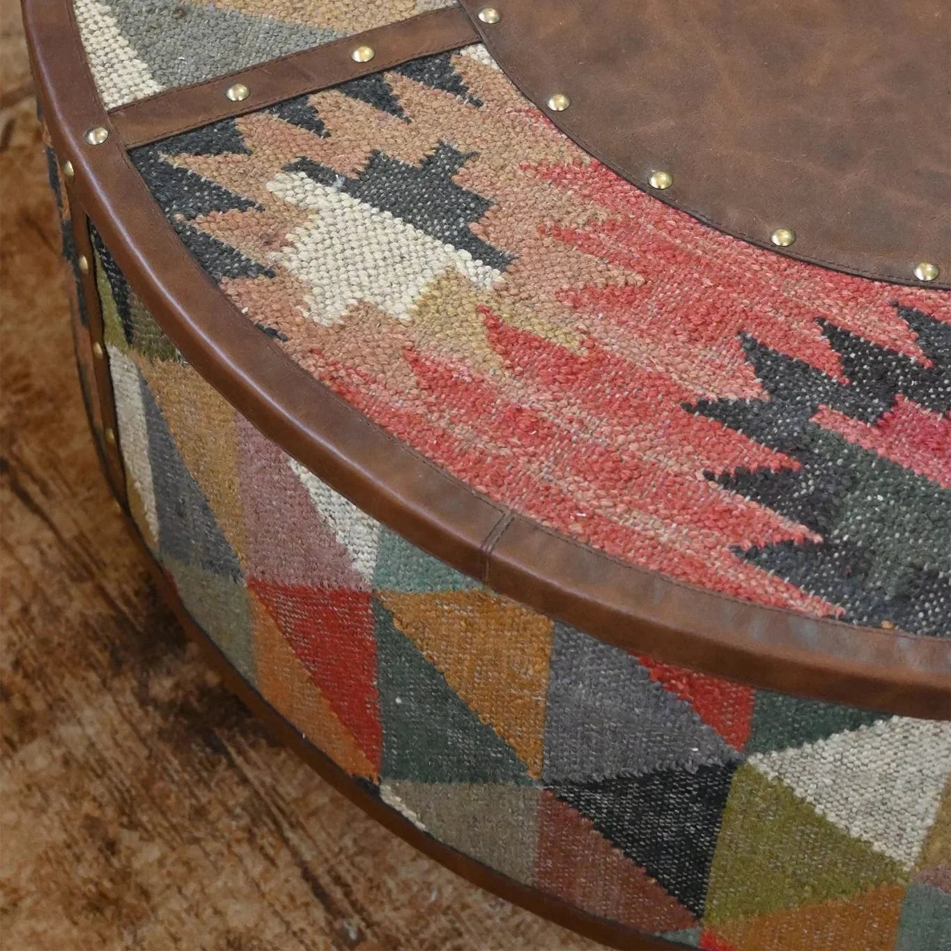 Round wooden table with a patterned fabric top on a wooden floor.