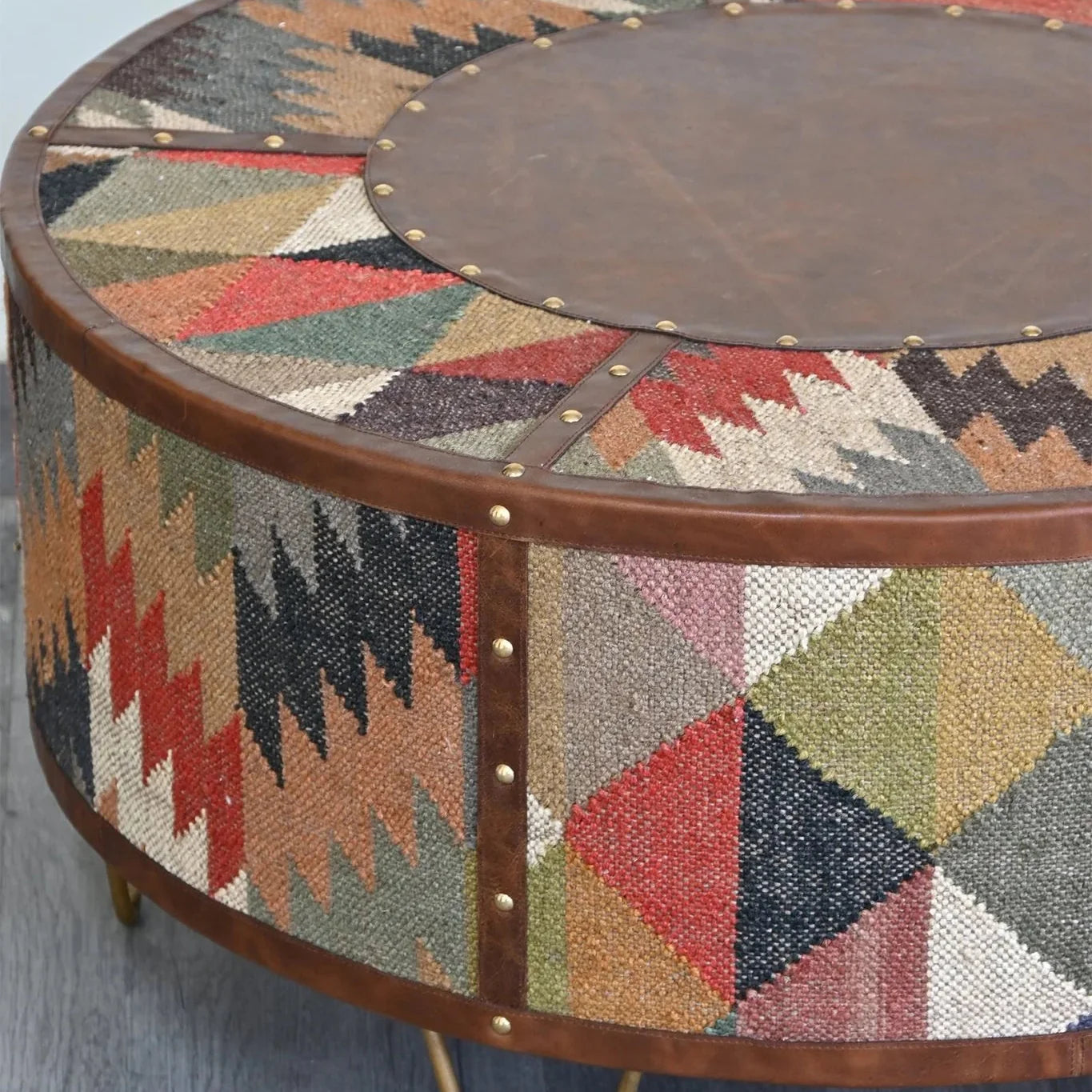 Round coffee table with geometric patterned top and wooden base on a light gray surface.